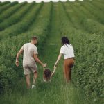 Happy family walking together through a lush green field enjoying nature and togetherness.